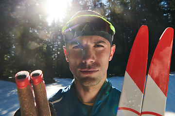 Image showing Portrait handsome male athlete with cross country skis in hands and goggles, training in snowy forest. Healthy winter lifestyle concept.