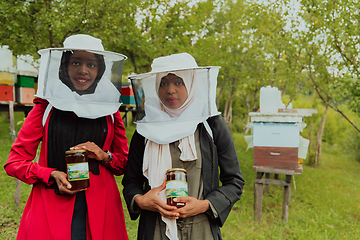 Image showing Portrait of an Arab investors holding a jar of honey in their hands while standing in front of a large honey farm. The concept of investing in small businesses