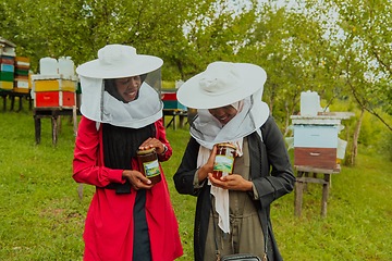 Image showing Portrait of an Arab investors holding a jar of honey in their hands while standing in front of a large honey farm. The concept of investing in small businesses