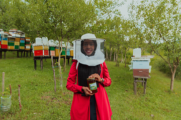 Image showing Portrait of a Muslim investitor in the beekeeping department of a honey farm holding a jar of honey in her hand