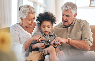 Image showing Grandparents, phone and child in home pointing, learning and bonding together in living room. Smartphone, biracial kid and grandpa and grandma in lounge streaming movie, video or film on social media