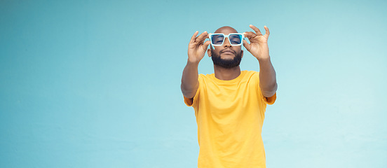 Image showing Black man, sunglasses and fashion on a blue background with cool and trendy style with mock up space. Young model person with eyewear in studio for advertising designer brand, logo or color in hands