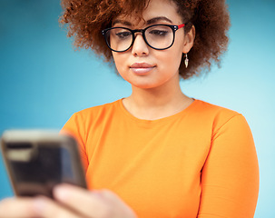 Image showing Woman, cellphone and mobile texting on blue background for social media, technology and network. Young female with smartphone technology in studio for connection, reading notification and website app