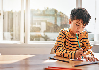 Image showing Drawing, education and a child in a house at a table for art, learning writing or creativity. Serious, morning and a kid with paper and color at a desk in a home for knowledge, studying or a picture