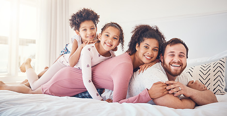 Image showing Interracial, happy family and portrait on a bed, bond and having fun on the weekend in their home together. Relax, love and face of playful children with parents in a bedroom, smile and playing games