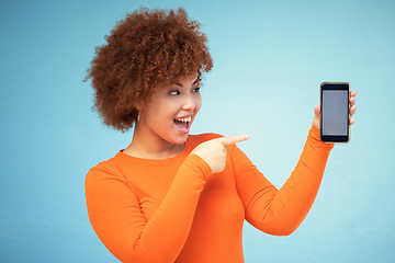 Image showing Woman, excited and phone mockup screen advertising sale, promotion or brand on website or internet. Person pointing hand at smartphone on blue background studio for about us or online winning deal