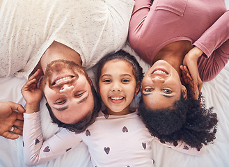 Image showing Happy family, smile and portrait on bed at home for quality time, bonding or morning routine. Above, mixed race and face of a man, woman and girl kid together in a bedroom with love, care and comfort