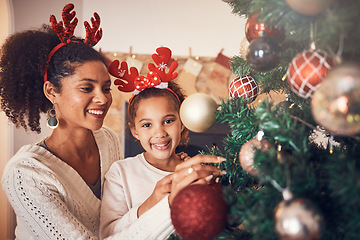 Image showing Christmas, portrait and mother with girl decorating tree, bonding and happy together. Xmas, smile and face of kid with African mom with ornament for family party, celebration or holiday event in home