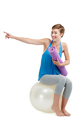 Image showing Pilates, pointing and woman isolated on a white background with balance ball for product placement on mockup. Happy fitness, exercise or workout person or yoga sports portrait show mockup in studio