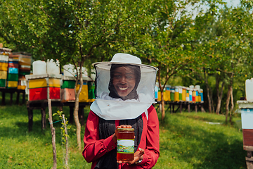 Image showing Portrait of Arab investitor in the beekeeping department of a honey farm holding a jar of honey in her hand