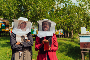 Image showing Portrait of a Arab investitors in the beekeeping department of a honey farm holding a jar of honey in her hand