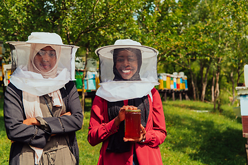 Image showing Portrait of a Arab investitors in the beekeeping department of a honey farm holding a jar of honey in her hand