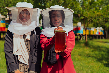 Image showing Portrait of a Arab investitors in the beekeeping department of a honey farm holding a jar of honey in her hand