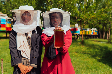 Image showing Portrait of a Arab investitors in the beekeeping department of a honey farm holding a jar of honey in her hand