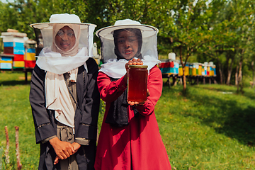 Image showing Portrait of a Arab investitors in the beekeeping department of a honey farm holding a jar of honey in her hand