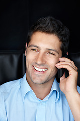Image showing No, you hang up. Shot of a handsome young businessman talking on his cellphone against a black background.