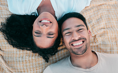 Image showing Portrait, picnic and smile with a couple on a blanket from above, lying down on the ground while on a date. Face, love or happy with a man and woman bonding together for romance on valentines day