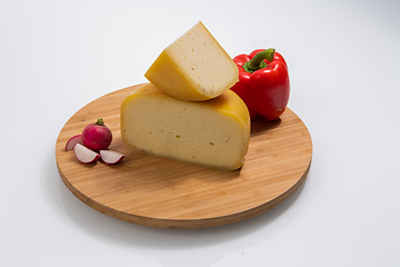 Image showing Bosnian traditional cheese served on a wooden container with peppers, parade and onions isolated on a white background