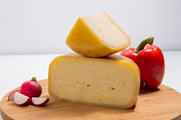 Image showing Bosnian traditional cheese served on a wooden container with peppers, parade and onions isolated on a white background