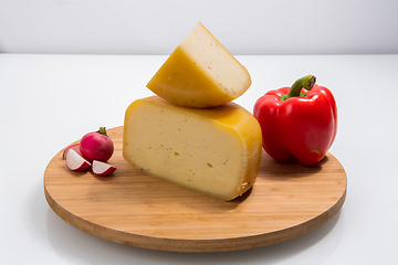 Image showing Bosnian traditional cheese served on a wooden container with peppers, parade and onions isolated on a white background