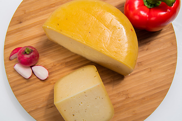 Image showing Bosnian traditional cheese served on a wooden container with peppers, parade and onions isolated on a white background