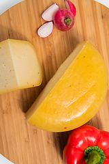 Image showing Bosnian traditional cheese served on a wooden container with peppers, parade and onions isolated on a white background