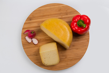 Image showing Bosnian traditional cheese served on a wooden container with peppers, parade and onions isolated on a white background