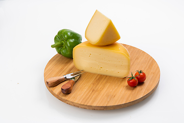 Image showing Bosnian traditional cheese served on a wooden container with peppers, parade and onions isolated on a white background