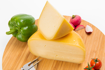 Image showing Bosnian traditional cheese served on a wooden container with peppers, parade and onions isolated on a white background