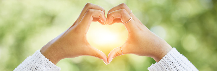 Image showing Love, heart and lens flare with hands of woman in nature for support, motivation and kindness. Thank you, peace and hope with closeup of person and sign in outdoors for emoji, health and banner