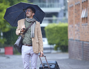 Image showing Thinking, travel and a man with an umbrella and suitcase in the rain in the morning. Serious, winter and a person with luggage for a vacation, immigration or holiday in the city for commute ideas
