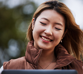 Image showing Happy, social media and a woman with a tablet in nature for online communication, app or email. Park, smile and a young Asian girl reading a conversation on technology, website or notification