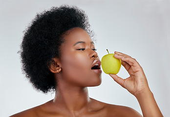 Image showing Black woman, hair and apple for natural nutrition, diet or vitamins against a white background in studio. Face of African female person eating organic fruit for healthy wellness, fiber or body care