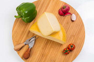 Image showing Bosnian traditional cheese served on a wooden container with peppers, parade and onions isolated on a white background