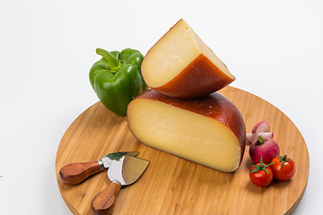 Image showing Bosnian traditional cheese served on a wooden container with peppers, parade and onions isolated on a white background