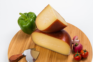 Image showing Bosnian traditional cheese served on a wooden container with peppers, parade and onions isolated on a white background