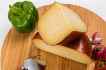 Image showing Bosnian traditional cheese served on a wooden container with peppers, parade and onions isolated on a white background