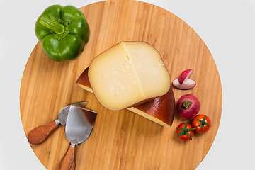 Image showing Bosnian traditional cheese served on a wooden container with peppers, parade and onions isolated on a white background