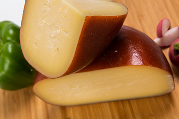 Image showing Bosnian traditional cheese served on a wooden container with peppers, parade and onions isolated on a white background