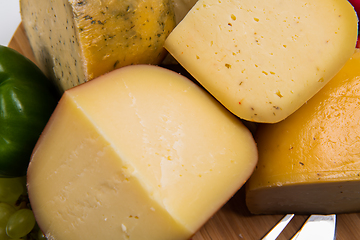 Image showing Bosnian traditional cheese served on a wooden container with peppers, parade and onions isolated on a white background