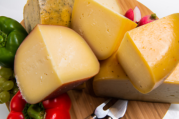 Image showing Bosnian traditional cheese served on a wooden container with peppers, parade and onions isolated on a white background