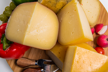 Image showing Bosnian traditional cheese served on a wooden container with peppers, parade and onions isolated on a white background