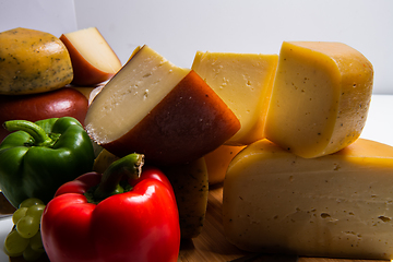 Image showing Bosnian traditional cheese served on a wooden container with peppers, parade and onions isolated on a white background