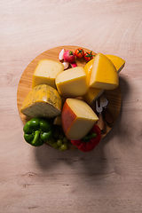 Image showing Bosnian traditional cheese served on a wooden container with peppers, parade and onions isolated on a white background