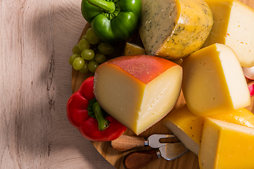 Image showing Bosnian traditional cheese served on a wooden container with peppers, parade and onions isolated on a white background