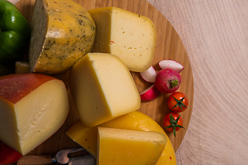 Image showing Bosnian traditional cheese served on a wooden container with peppers, parade and onions isolated on a white background