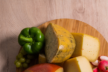 Image showing Bosnian traditional cheese served on a wooden container with peppers, parade and onions isolated on a white background