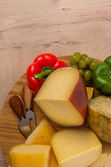 Image showing Bosnian traditional cheese served on a wooden container with peppers, parade and onions isolated on a white background