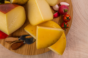 Image showing Bosnian traditional cheese served on a wooden container with peppers, parade and onions isolated on a white background