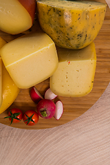 Image showing Bosnian traditional cheese served on a wooden container with peppers, parade and onions isolated on a white background